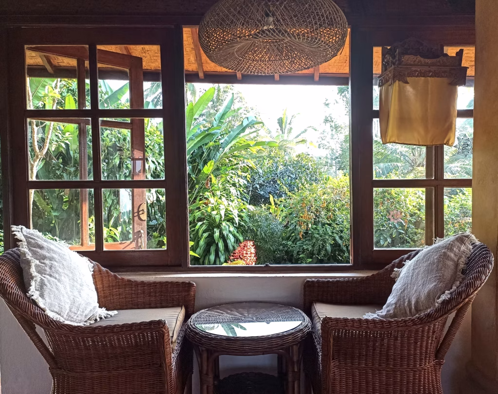A cosy window nook with rattan chairs overlooking a tropical garden at the Bali lodge