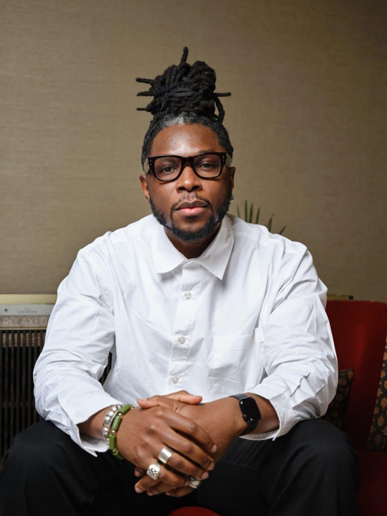 Portrait of writer and retreat co-host Yomi Sode, wearing glasses and a white shirt